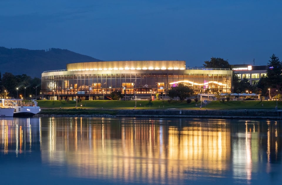 Beleuchtetes Brucknerhaus Linz am Ufer der Donau bei Nacht