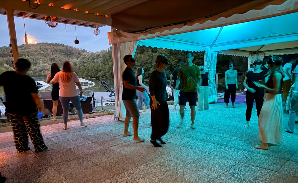 Gruppe tanzt bei einsetzender Dämmerung im blauen Licht am Salmsee