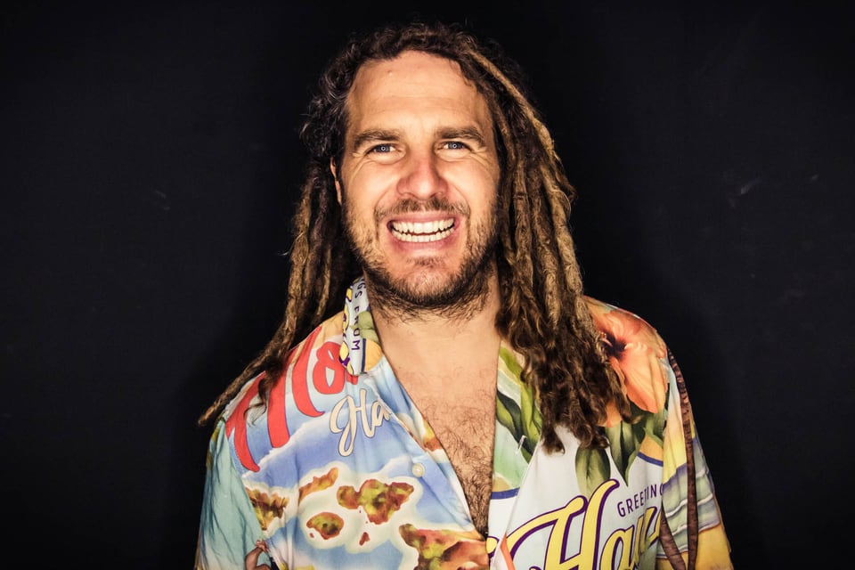 Daniel Fetzy Fetz lächelt im bunten Hawaiihemd vor schwarzem Hintergrund
