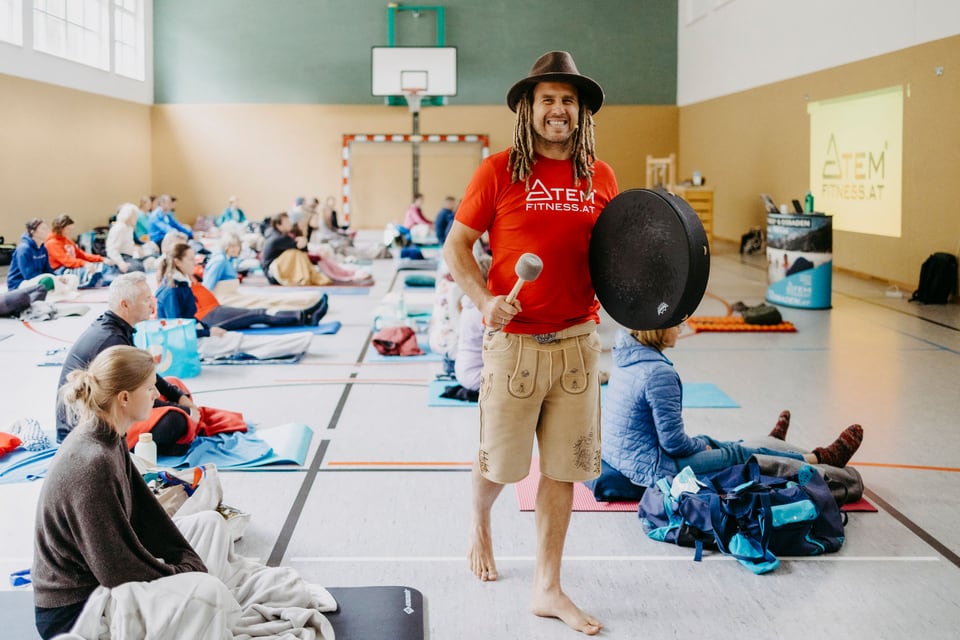 Daniel Fetz steht lächelnd mit einer Rahmentrommel vor der Workshopgruppe