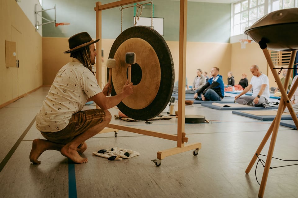 Daniel Fetz spielt vor einer Atemfitness Gruppe einen großen Gong