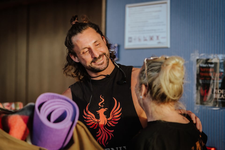 James McCauley begrüßt eine Teilnehmerin mit Yogamatte