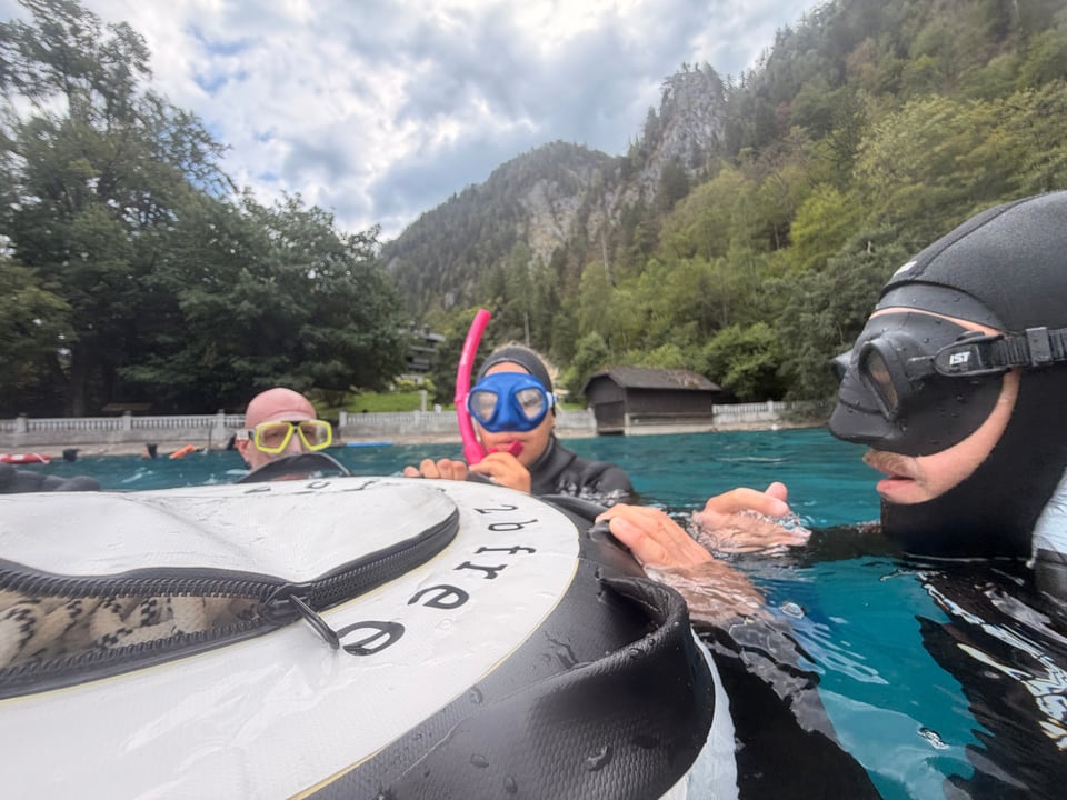 Teilnehmende mit Tauchmasken an der Boje vor dem Seeufer