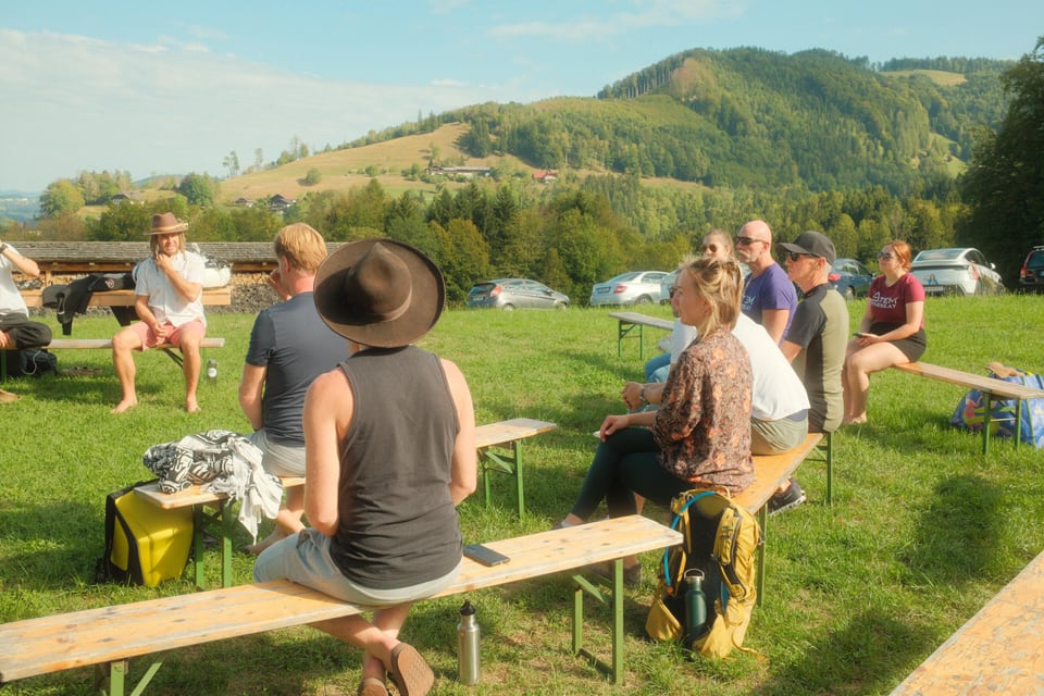 Gruppe sitzt zum Austausch auf Bänken auf der Wiese