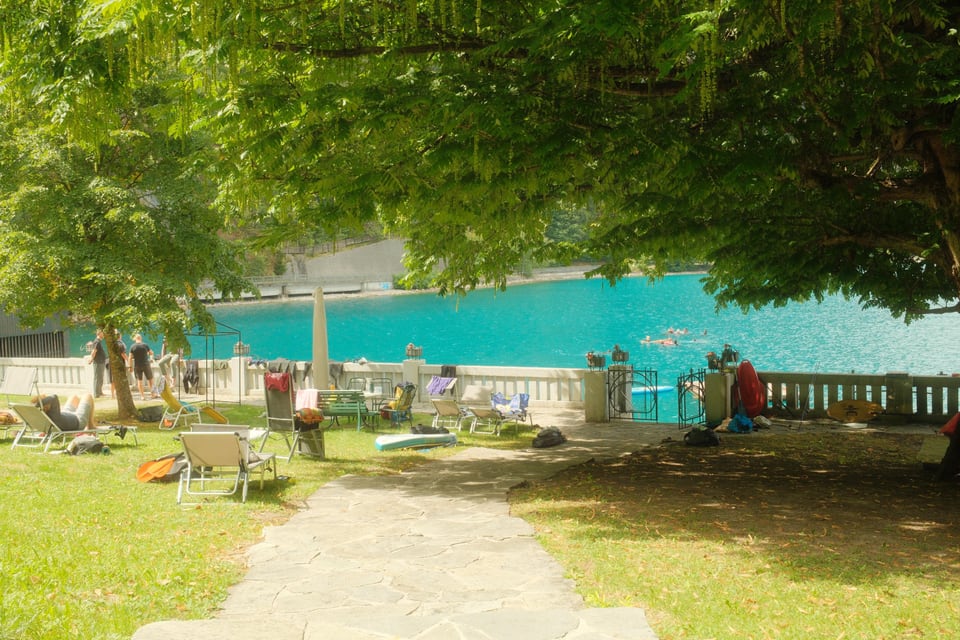 Weg unter Bäumen zum türkisfarbenen Attersee