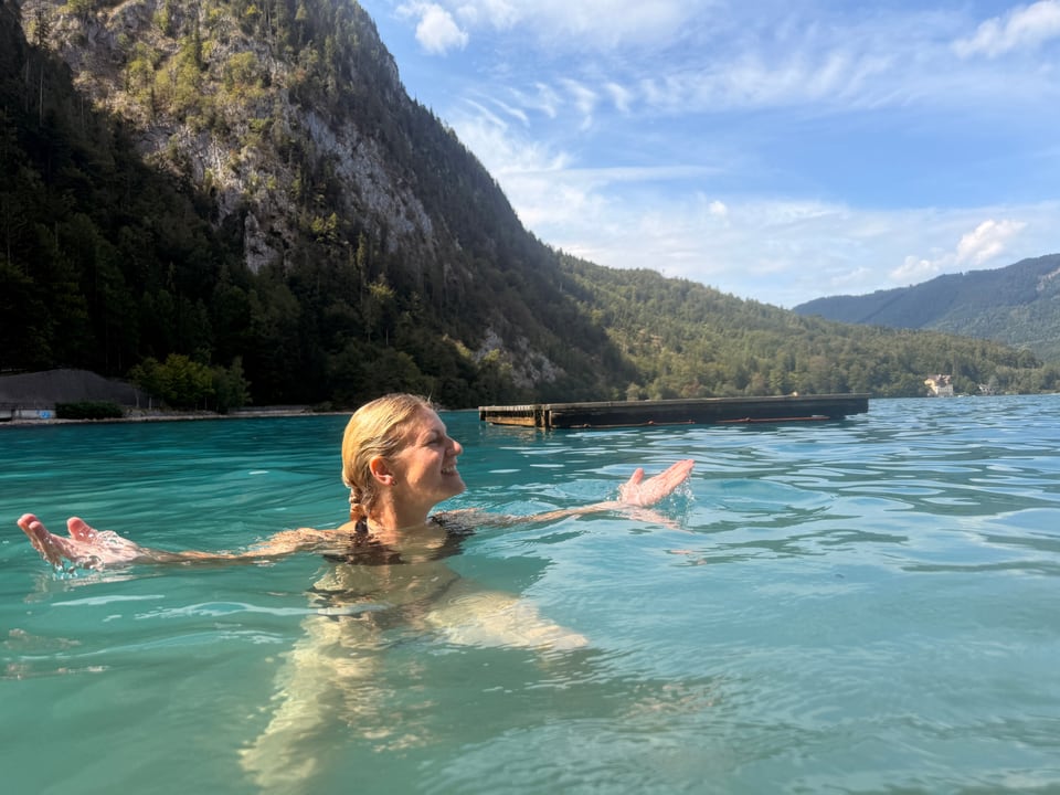 Teilnehmerin im Attersee vor bewaldeten Bergen