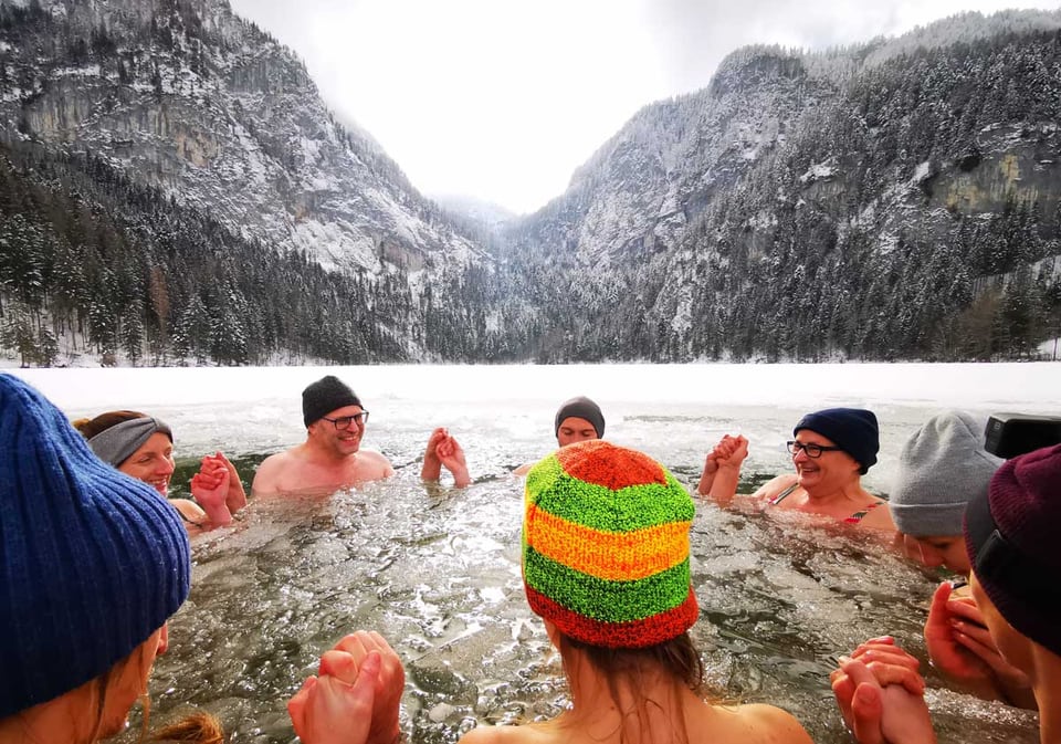 Retreatgruppe badet gemeinsam im Eisloch am verschneiten Gleinkersee
