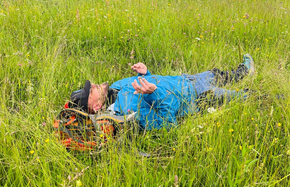 Teilnehmer liegt nach einer Atemübung entspannt in der Bergwiese