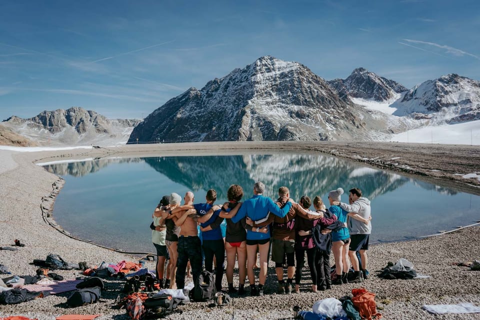 Retreatgruppe vor einem klaren Bergsee und schneebedeckten Gipfeln im Pitztal
