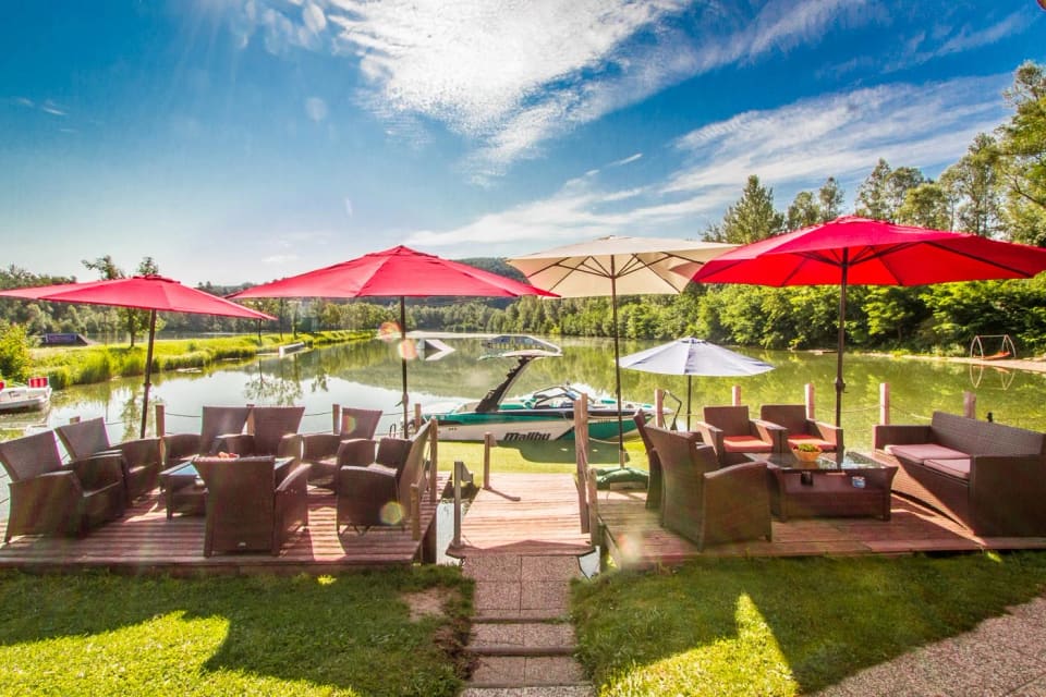 Sonnige Terrasse mit roten Schirmen direkt am Salmsee