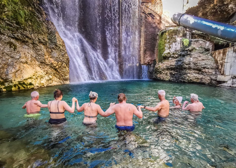 Retreatgruppe beim gemeinsamen Eisbad unter einem Wasserfall