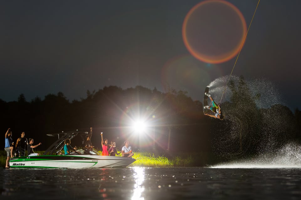 Daniel Fetz springt nachts mit dem Wakeboard hinter einem beleuchteten Boot
